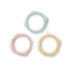 Three silicone teething rings in pastel colors on a white background
