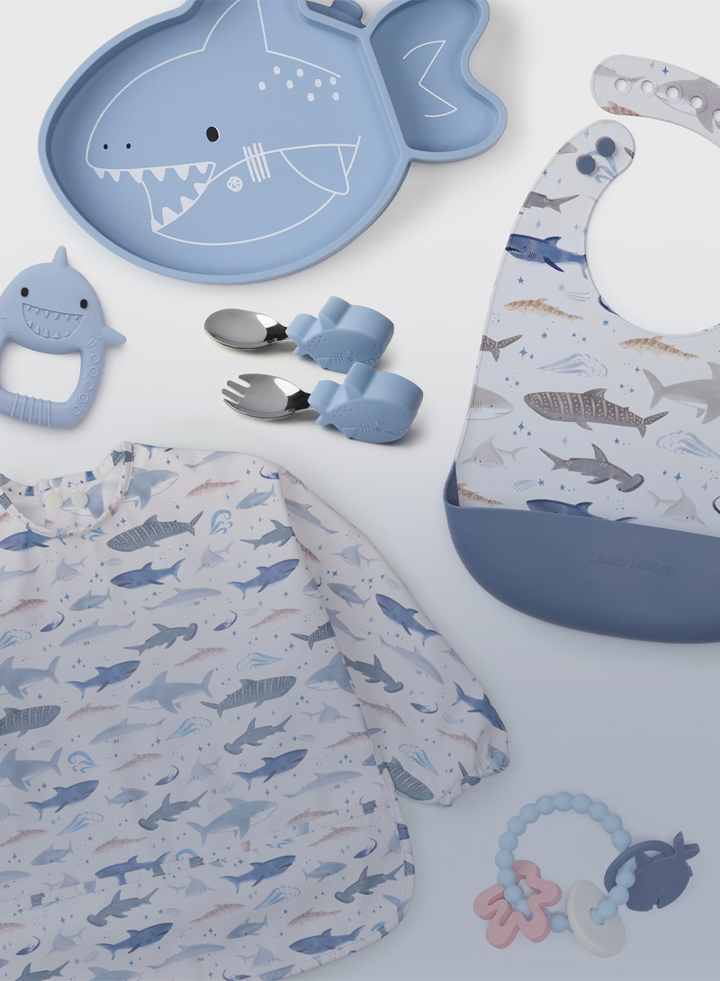 Collection of baby products with shark patterns on a light blue background